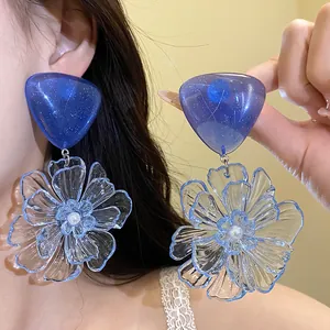 Detailed view of blue resin flower drop earrings with sparkling heart-shaped studs.