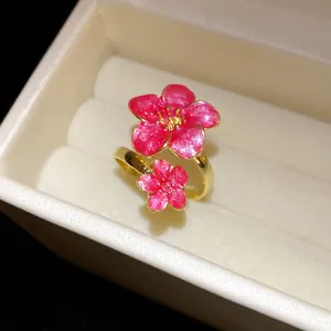 Elegant close-up of pink enamel flower gold adjustable ring in a cream jewelry box