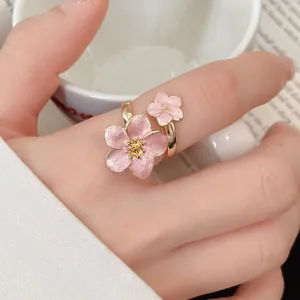 Close-up of elegant pink enamel cherry blossom ring with adjustable gold-tone band