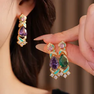 Close-up of vintage palace style drop earrings with colorful zircons and teal enamel.