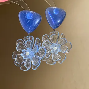 Detailed view of blue heart and transparent flower resin earrings with elegant silver needles