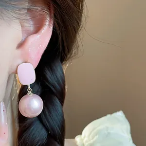 Close-up view of French style pink enamel square pearl drop earrings worn by a model.