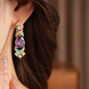 Detailed view of vintage palace style earrings with teardrop purple stones and turquoise enamel