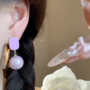 Close-up of French style purple dripping oil square stud with pearl drop on ear.