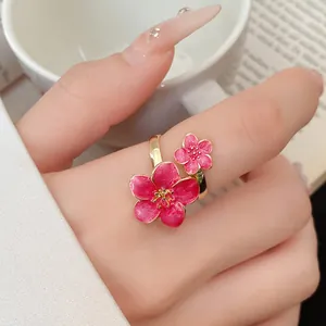 Close-up view of a vintage style pink enamel flower adjustable ring worn on a finger