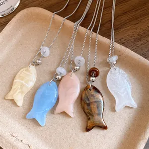 Vue détaillée de cinq colliers avec pendentif poisson en résine sur un plateau