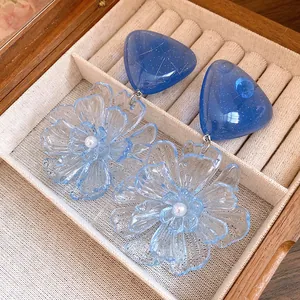 Macro view of blue resin flower earrings with pearlescent center and gold flecked studs