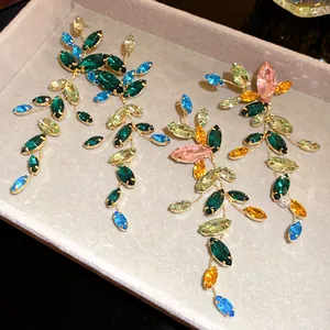 Close-up of elegant marquise rhinestone leaf drop earrings on a beige velvet tray