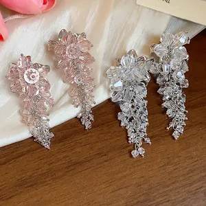 Detailed view of elegant pink and clear crystal flower tassel earrings on silk background