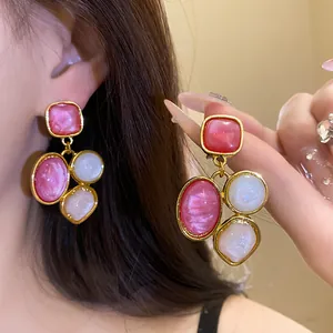 Detailansicht der geometrischen rosa Harz-Ohrhänger im Retro-Stil an einem Modell