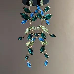 Detailed view of elegant leaf-style earrings with green and blue marquise rhinestones.