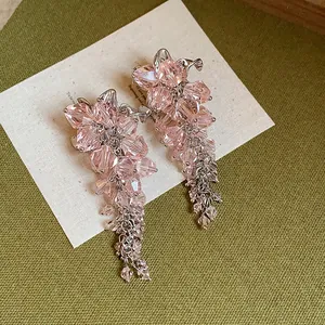 Close-up of pink faceted glass bead flower tassel earrings on textured background