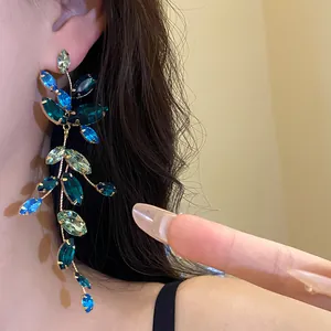 Detailed close-up of elegant long tassel earrings with blue and green marquise crystals.