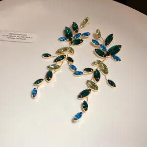Macro view of elegant leaf-shaped drop earrings featuring blue and green crystals