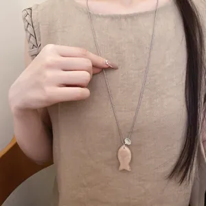 Vue détaillée d'un collier avec pendentif poisson en résine pêche sur une chaîne en argent