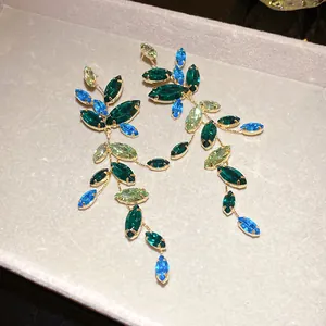 Detailed view of leaf-shaped tassel earrings featuring vibrant blue and green crystals