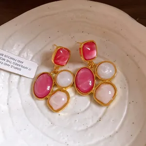 Nahaufnahme französischer Vintage-Resin-Ohrhänger mit rosa und weißen Steinen.