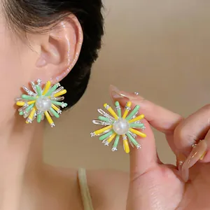 Detailed view of floral sunburst stud earrings with pearl center on ear and hand
