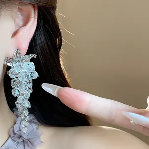 Detailed macro view of elegant silver crystal flower tassel drop earrings worn by model