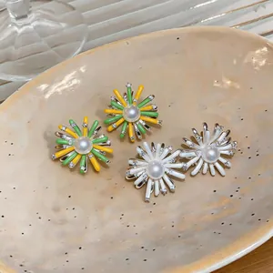 Close-up of colorful enamel flower earrings with central pearls and small rhinestones