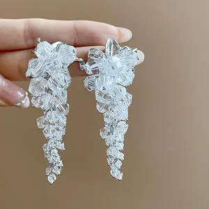 Close-up of elegant silver tassel earrings with clear glass beads in a floral design.