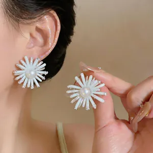 Detailed view of white sunburst flower earrings with pearl center and crystal accents