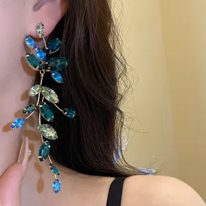 Close-up of elegant long tassel earrings with colorful marquise crystals on a model