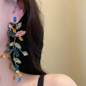 Detailed view of long tassel earrings with colorful marquise-cut rhinestones on ear.