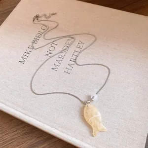 Vue détaillée d'un pendentif en forme de poisson en résine sur une chaîne fine
