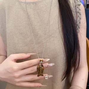 Vue détaillée d'un collier avec pendentif poisson en résine porté par un mannequin.
