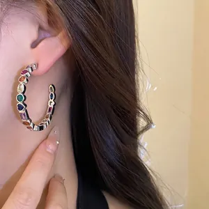 Elegant silver-tone C-shape hoop earrings with multi-colored geometric zircon stones on model