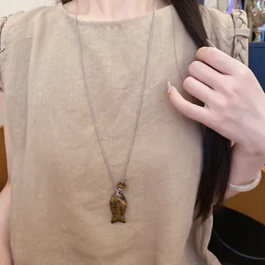 Gros plan d'un collier avec pendentif en forme de poisson en résine porté par un mannequin