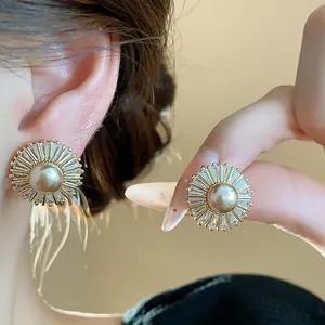 Close-up of elegant vintage-style pearl and zircon starburst stud earrings on ear.