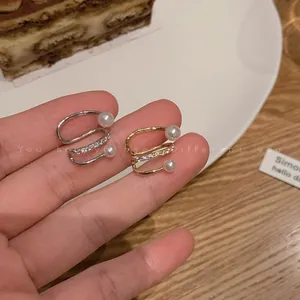 Macro view of gold and silver tone zircon ear cuffs featuring white pearls for non-pierced ears