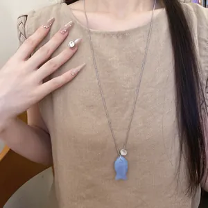 Collier à pendentif poisson en résine bleue porté par un mannequin asiatique élégant