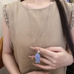Gros plan d'un collier avec pendentif poisson en résine bleue porté par un mannequin
