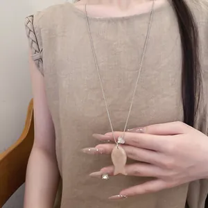 Vue détaillée d'un petit pendentif poisson en résine sur un collier argenté