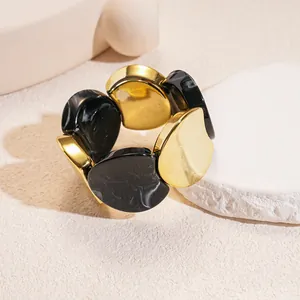 Close-up of a luxury gold-tone and black marbled acrylic chunky round stretch bracelet