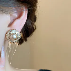 Close-up of vintage sunburst earrings with a central pearl and baguette zircons