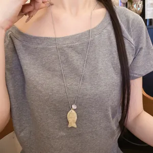 Vue détaillée d'un collier avec un pendentif poisson en résine sur un mannequin.