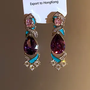 Detailansicht luxuriöser Tropfenohrringe mit violetten Edelsteinen und Emaille-Akzent.