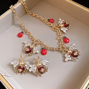 Vintage style enamel insect necklace and earring set with rhinestones and gold chain.