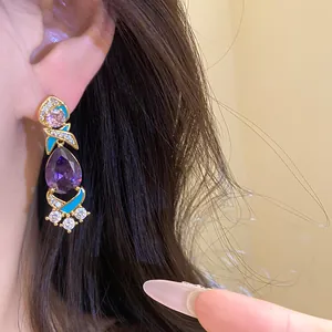 Nahaufnahme des violetten Zirkonia-Ohrrings mit türkisfarbener Emaille und goldenem Finish