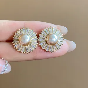 Detailed view of sunburst pearl stud earrings with zircon stones and gold-plated finish