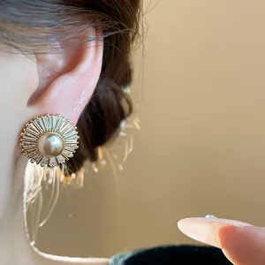 Close-up of elegant vintage gold pearl earrings with sparkling zircon sunburst design