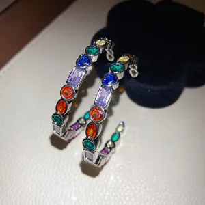 Exquisite detail of C-shaped silver earrings with multi-colored geometric zircon crystals.