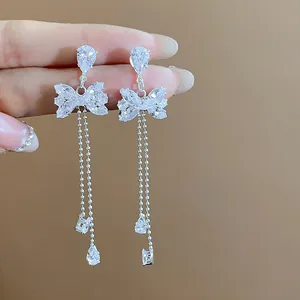 Close-up detail of elegant sparkling bowknot tassel dangle earrings featuring clear zircon stones