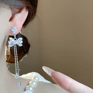 Close-up of sparkling cubic zirconia bow tassel earrings with elegant silver needle finish