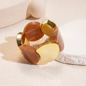 Close-up of acrylic and gold-toned circular panels on a retro elastic bracelet.