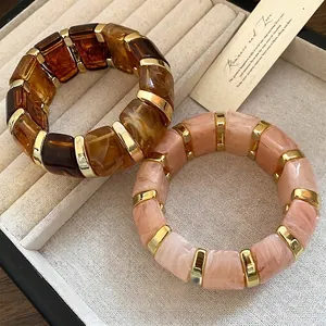 Deux bracelets élastiques en résine géométrique avec motifs marbre et dorures.